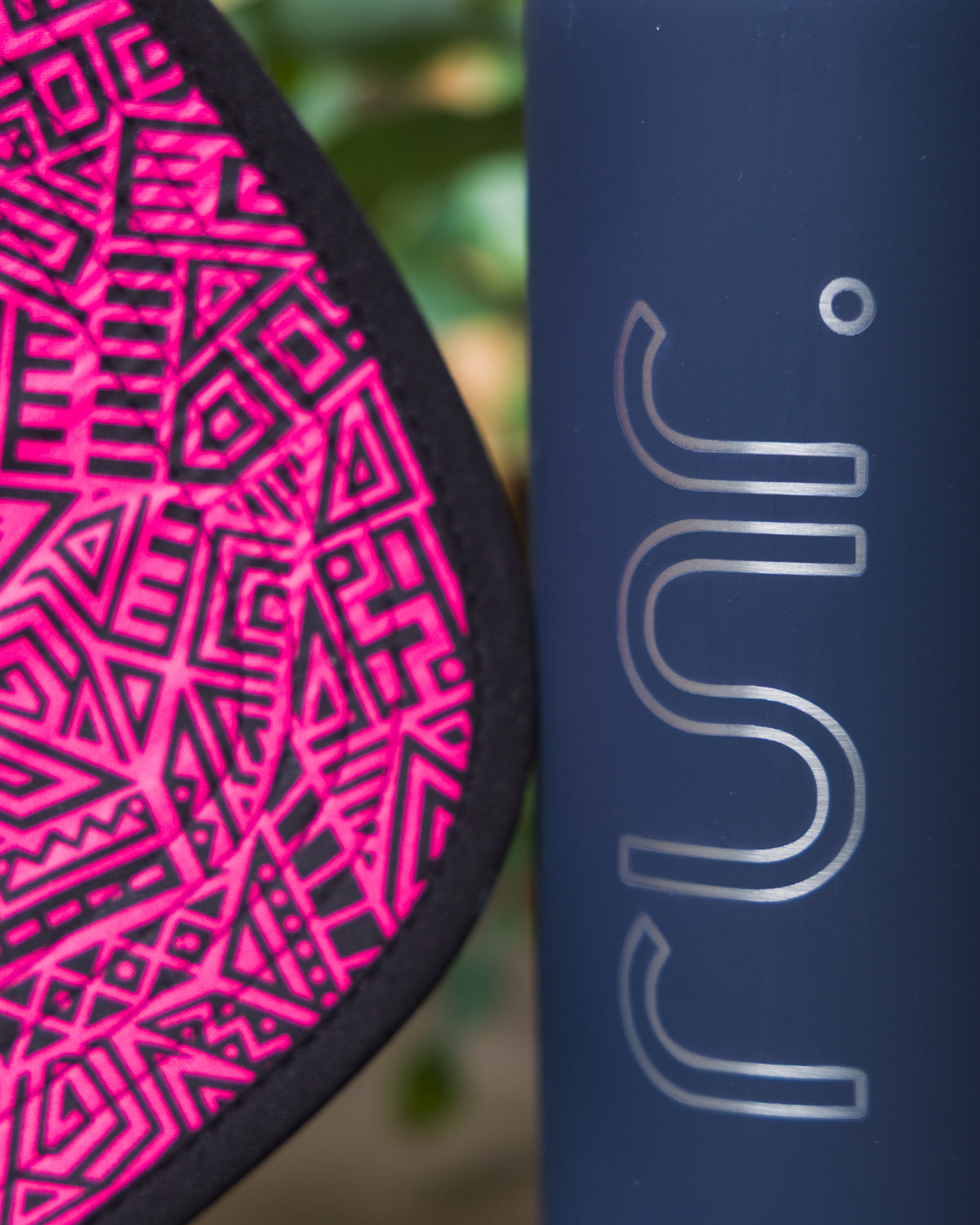 Black cap brim close-up with pink geometric logo pattern.