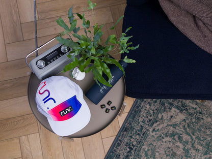 White technical running cap lying on a round table with runr logo patch