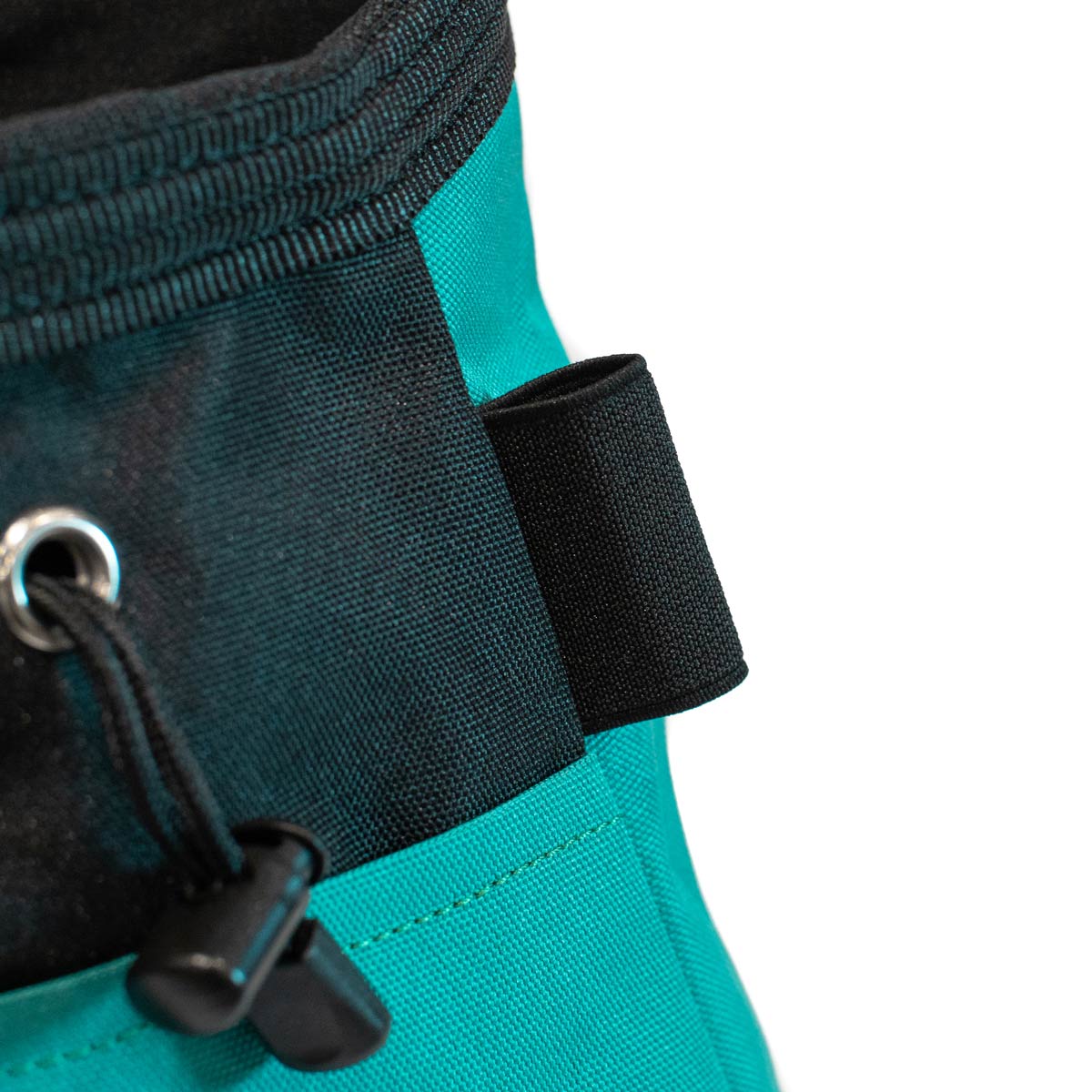 Bouldering chalk bucket close-up, black loop and adjustable webbing strap on turquoise