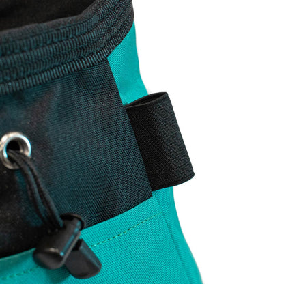 Bouldering chalk bucket close-up, black loop and adjustable webbing strap on turquoise