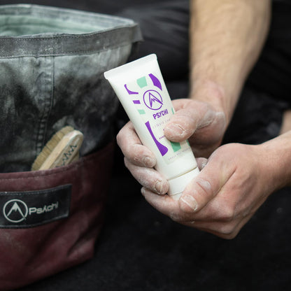 Hands applying liquid chalk from a squeeze tube, white PSYCHI purple logo tube