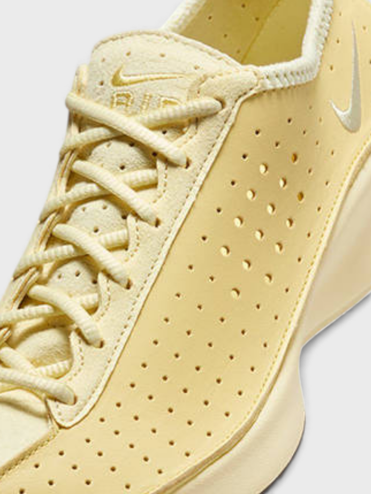 Soft yellow Nike lace-up upper with perforations and swoosh logo.