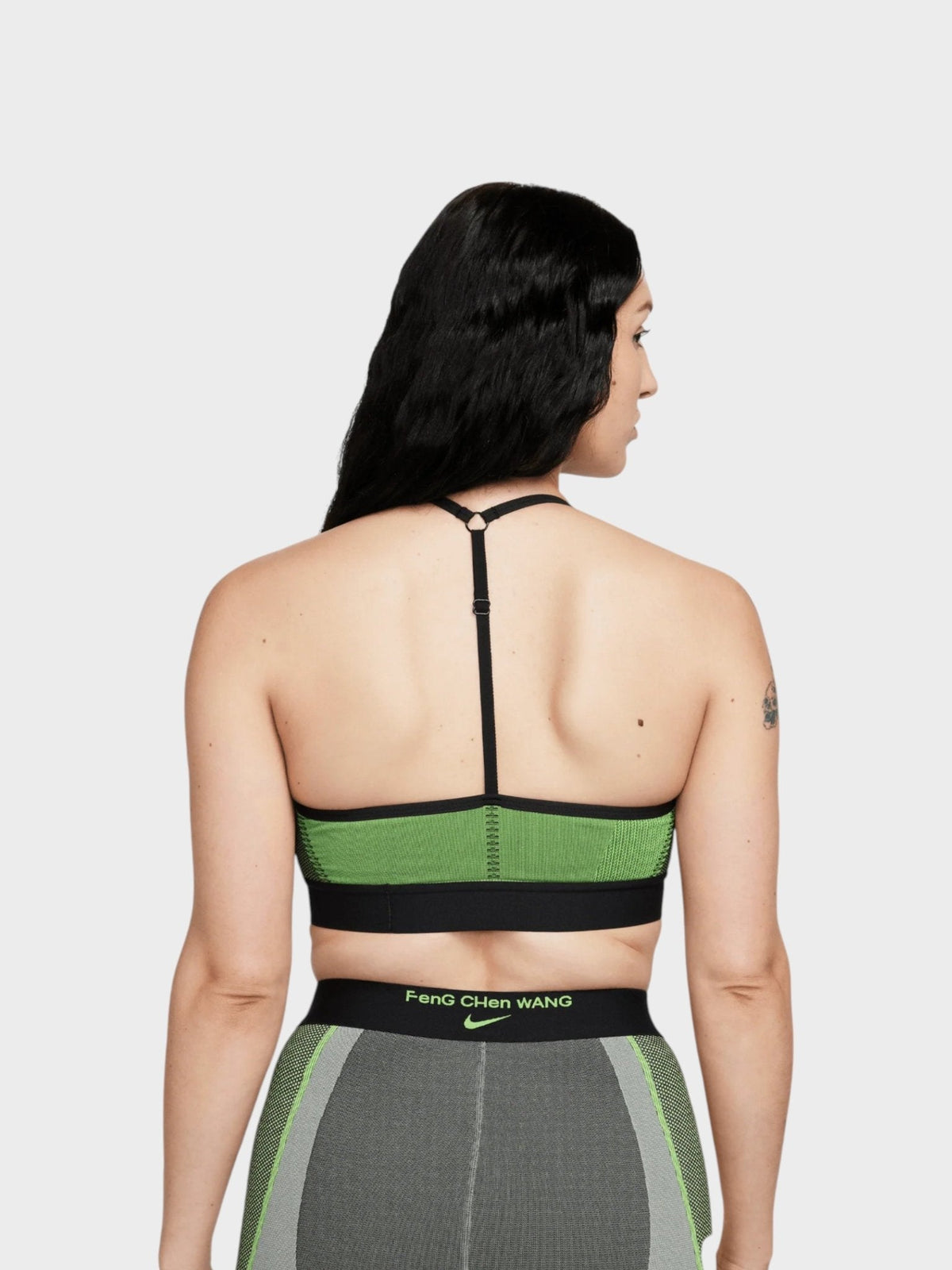 Back view: green sports bra with black racerback straps and vertical center seam