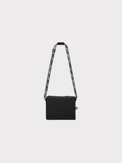 Black Nike crossbody bib bag with patterned shoulder strap and small front pocket