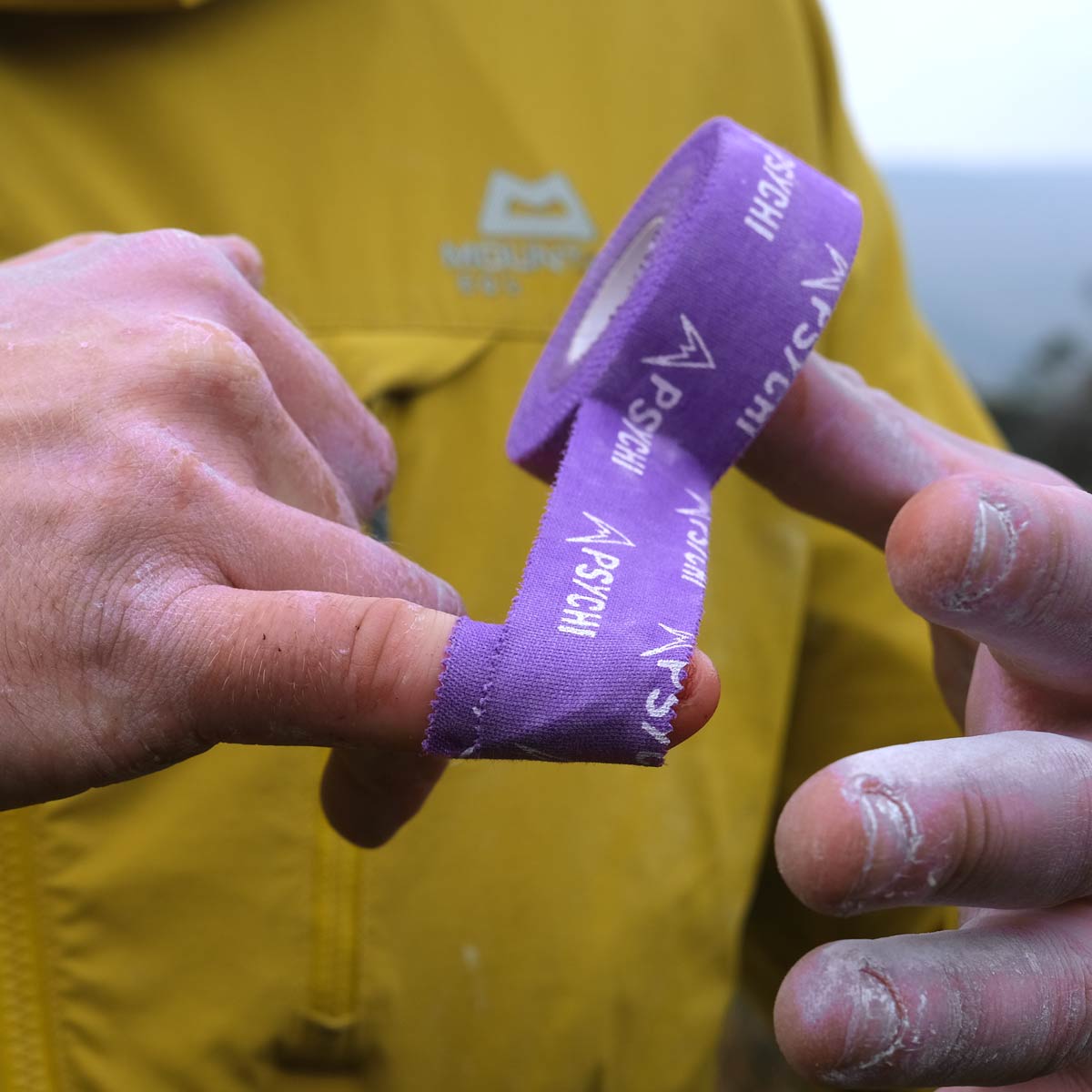 Finger tape applied to a climber’s finger using purple PSYCHI tape strip.