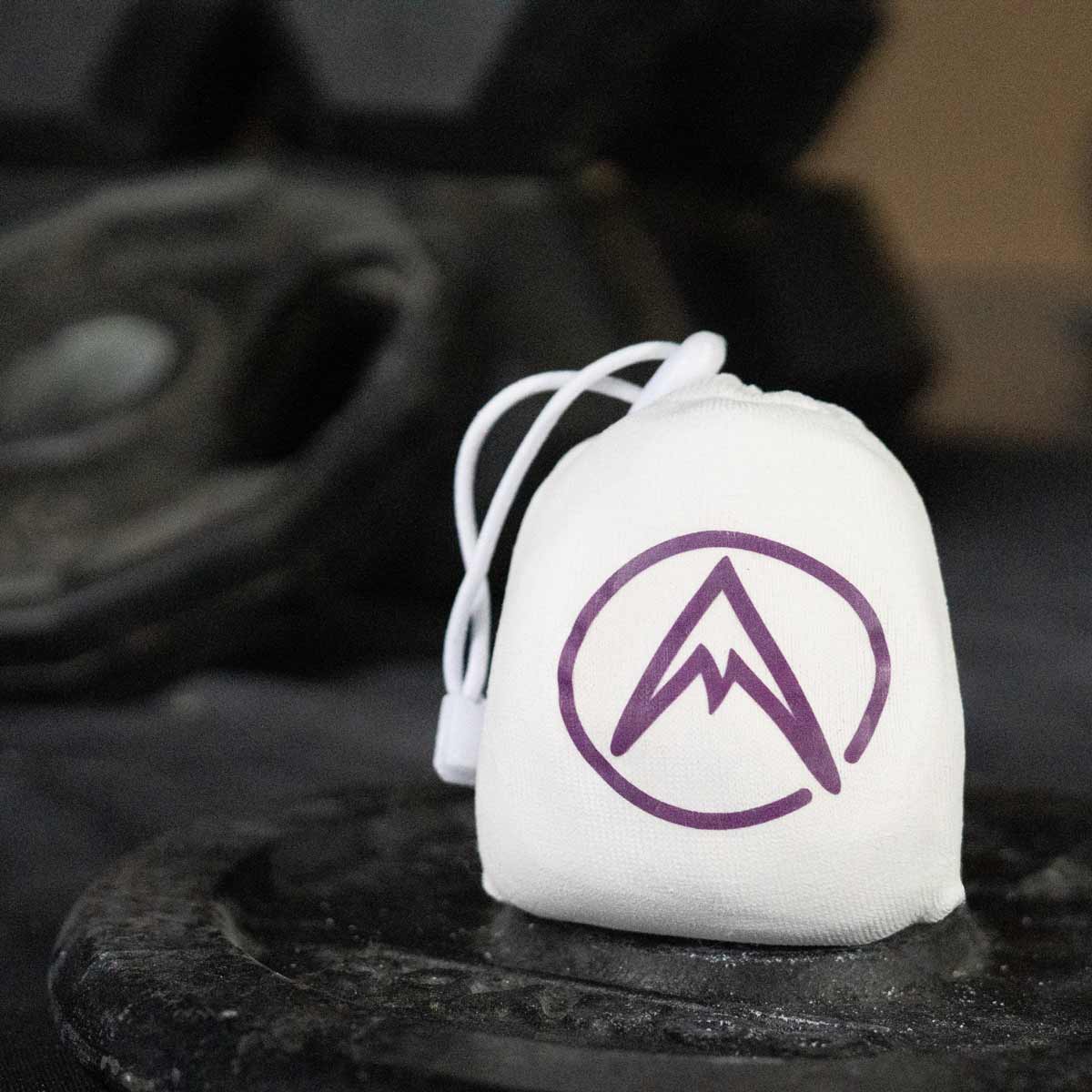 White refillable climbing chalk ball pouch with purple mountain logo and white draw cord.