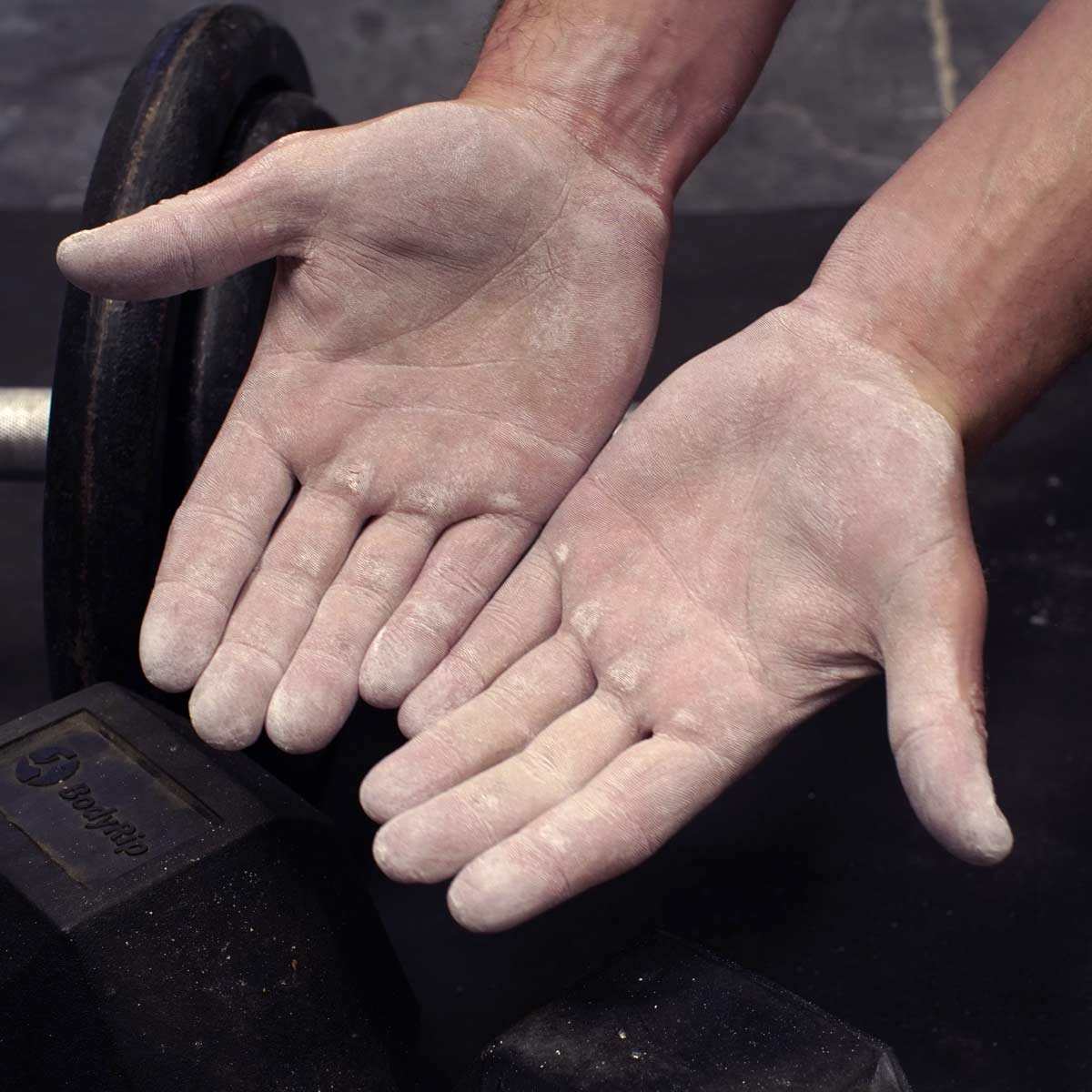 Climbing chalk powder on palms, white chalk dusted across dark climbing holds
