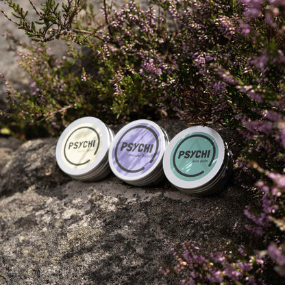 Three PSYCHI beeswax balm tins with different colored labels
