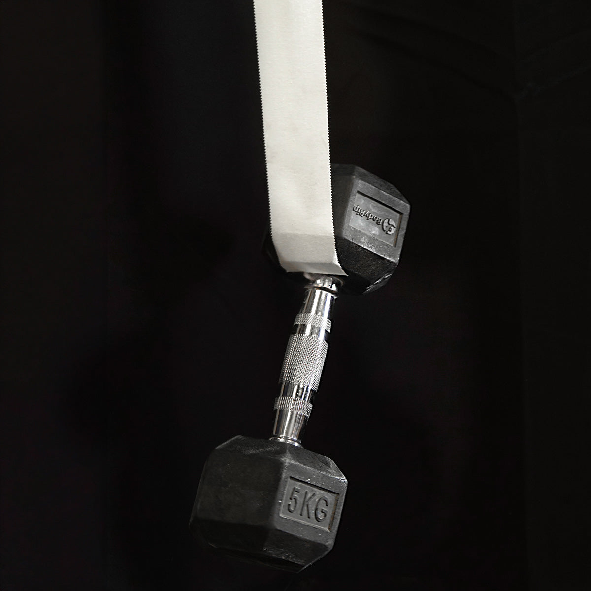 Climbing finger tape attached to a gym strap with metal dumbbell nearby