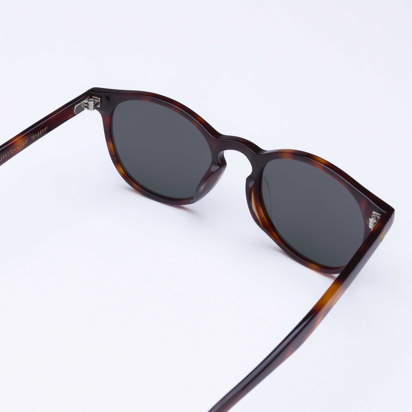 Tortoise shell sunglasses in angled view with dark lenses and metal hinges