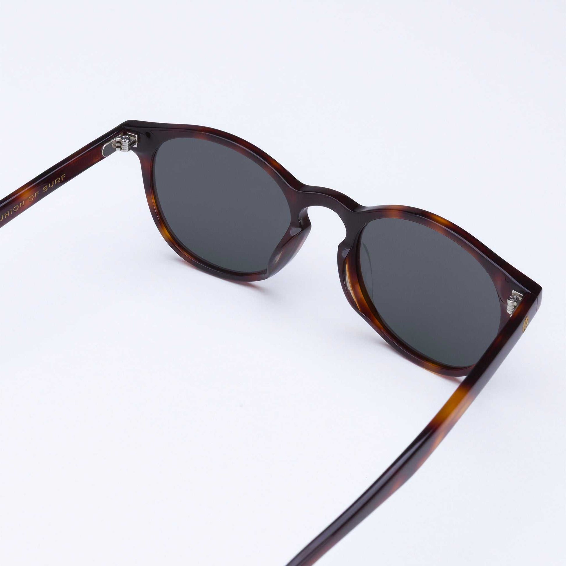 Tortoise shell sunglasses in angled view with dark lenses and metal hinges