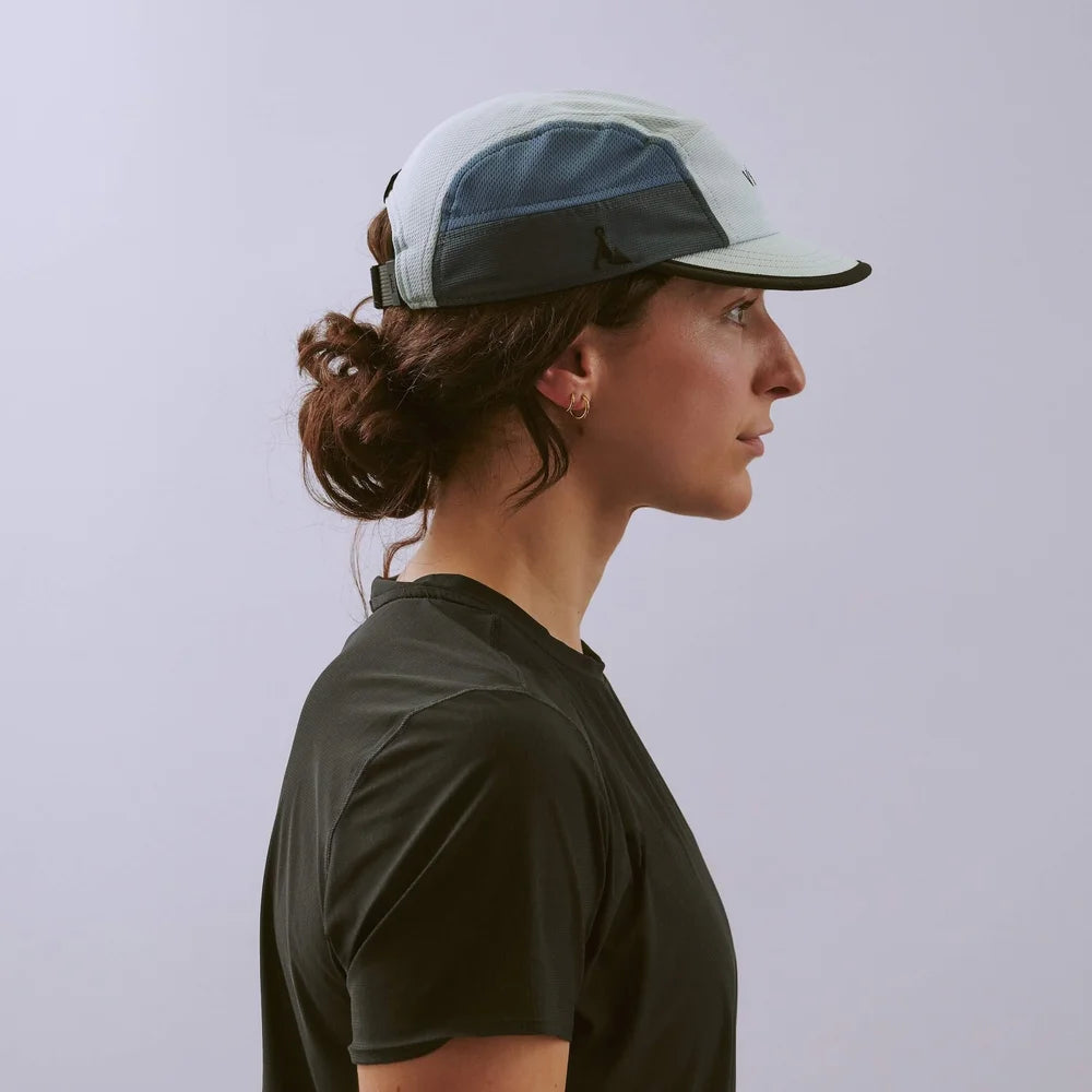 Person wearing a white cap with a mesh design on a plain background