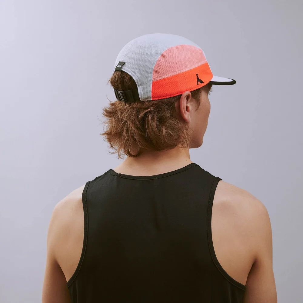 Person wearing a black tank top and a colorful cap on a gray background