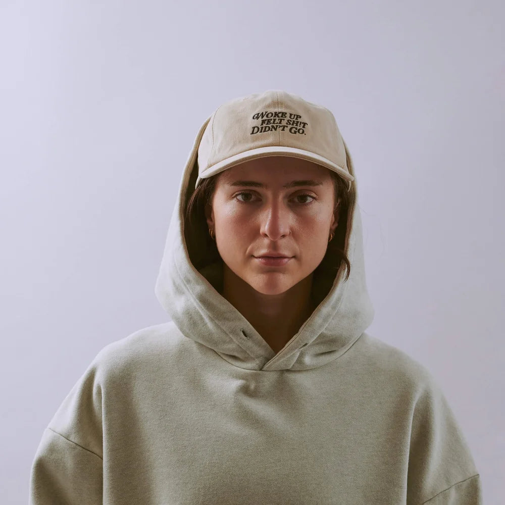 Person wearing a beige hoodie and cap with text on a plain background