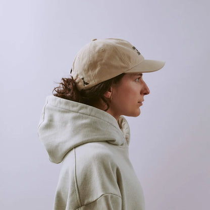 Person wearing a beige cap and hoodie against a plain background