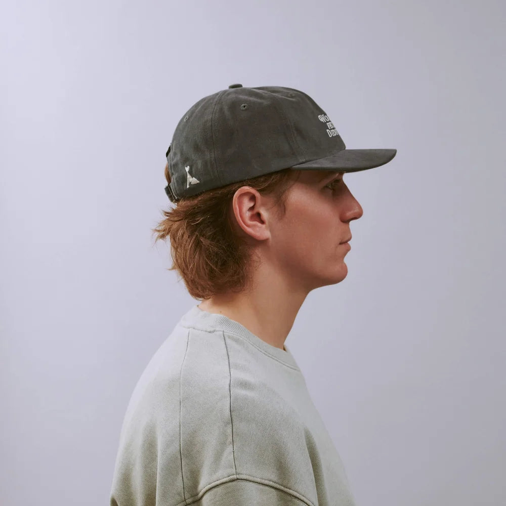 Person wearing a gray cap with a logo on a plain background