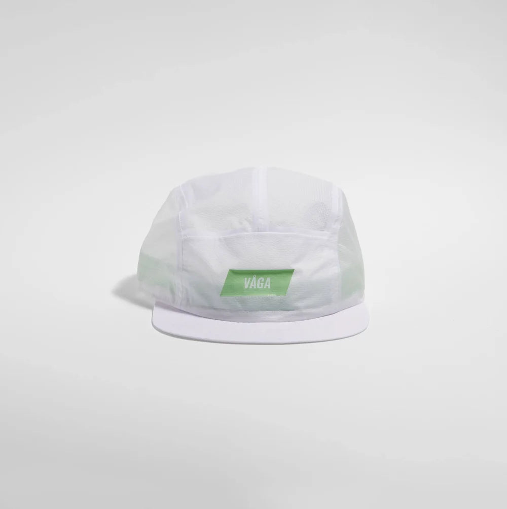 A white 5-panel camp cap with a green rectangular patch on the front displaying the white 'VAGA' brand name, set against a light gray studio background.