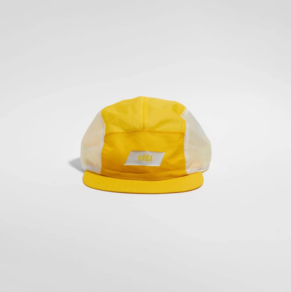 A yellow and white 5-panel camp cap with a yellow visor and a small white rectangular patch on the front, photographed on a light gray studio background.