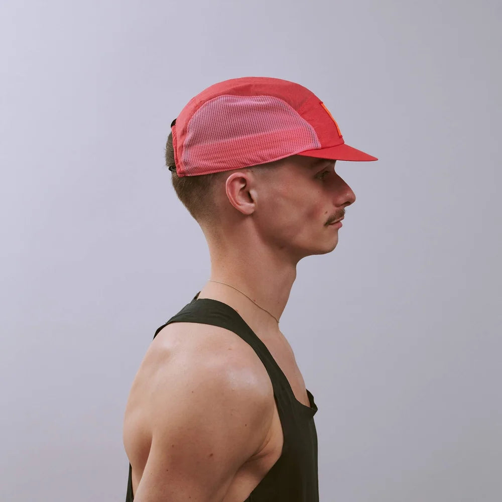 Man wearing a red cap and black tank top against a gray background