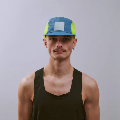 Man wearing a blue and green cap against a gray background