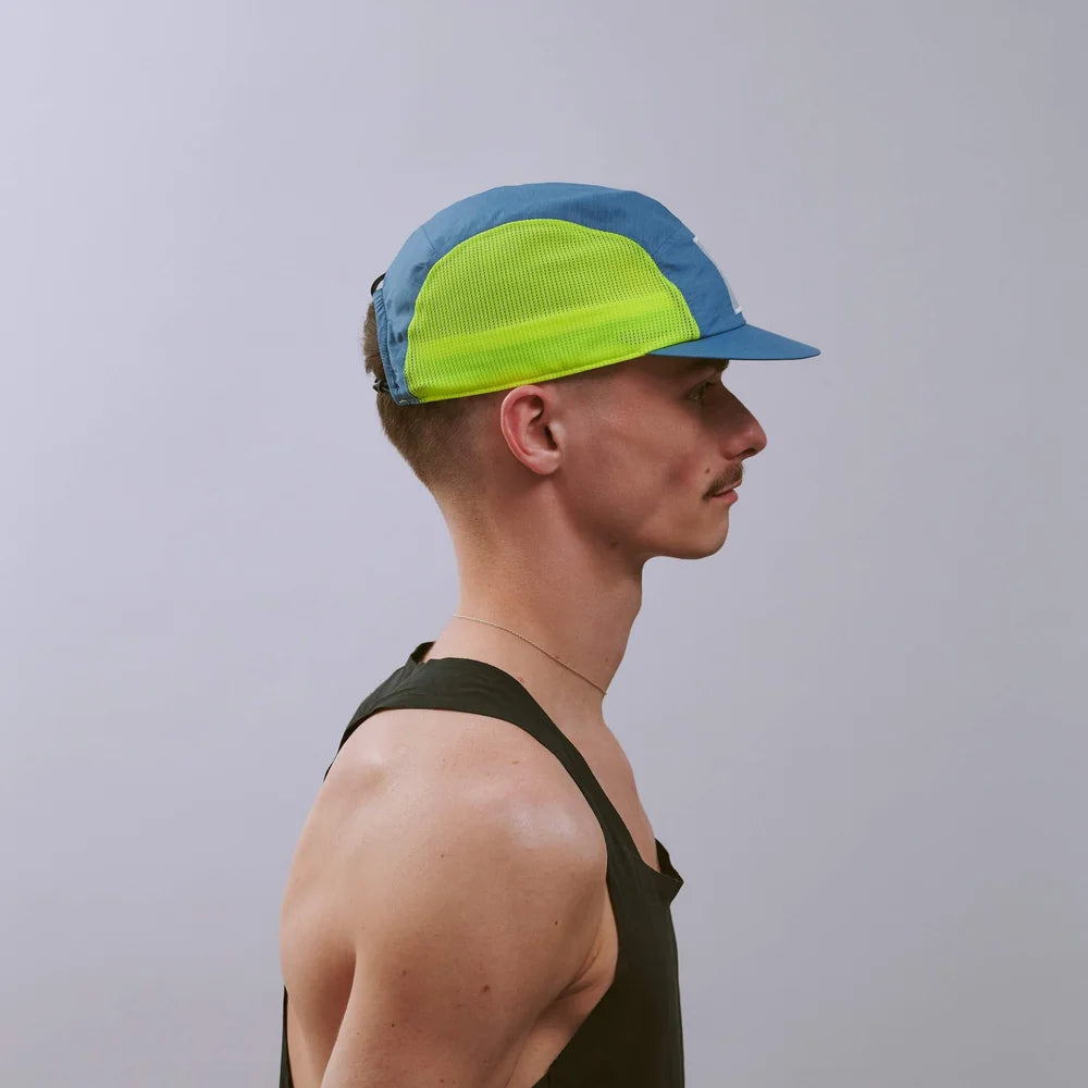 Man wearing a blue and green cap against a plain background
