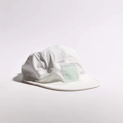 A light gray 5-panel camp cap with a small pale green rectangular patch on the front, photographed on a clean white studio background.