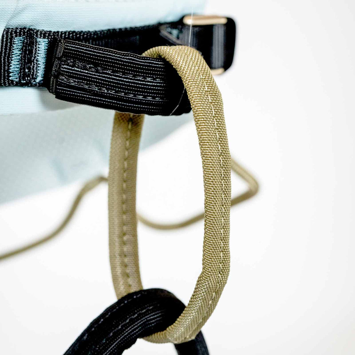 Climbing harness strap connector with black webbing and tan adjust loop, metal hardware