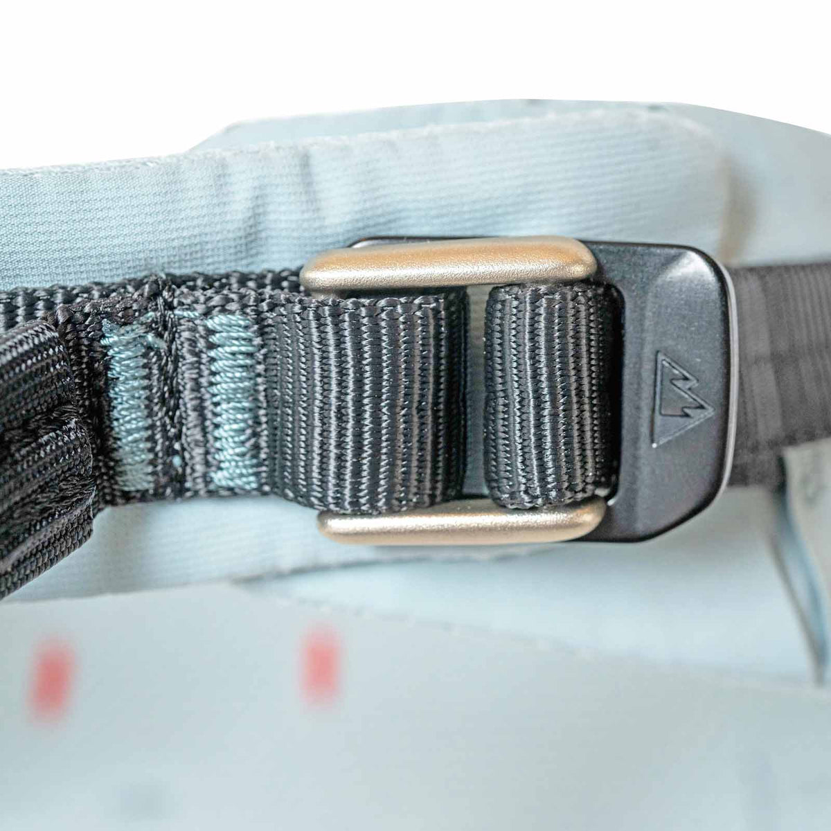 Light blue climbing harness buckle with blue-gray metal adjust piece and stitched webbing